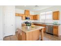 Well-equipped kitchen featuring an island, wood cabinets, stainless steel appliances and granite countertops at 909 Trinity Pond Cir, Henderson, NV 89002