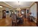 Refined dining room featuring a chandelier, hardwood floors, and a decorative hutch with plush upholstered chairs at 1704 River Birch St, Las Vegas, NV 89117