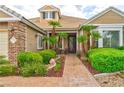 Inviting home exterior showcasing a brick pathway, manicured bushes, and decorative palm trees near the front door at 1704 River Birch St, Las Vegas, NV 89117