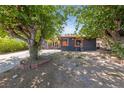 A single-story home with black exterior paint, contrasting orange trim and mature trees in the front yard at 1916 Canosa Ave, Las Vegas, NV 89104
