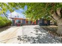 Charming home with black paint, vibrant orange trim, a spacious driveway, and a mature tree offering plenty of shade at 1916 Canosa Ave, Las Vegas, NV 89104