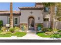 Inviting front entrance featuring a decorative wrought iron gate, lush plantings, and stone accents at 2436 Grassy Spring Pl, Las Vegas, NV 89135
