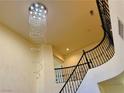 A winding staircase is illuminated by a dazzling chandelier at 2448 Ram Crossing Way, Henderson, NV 89074