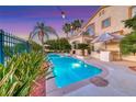 Relax in the backyard oasis featuring a sparkling pool, mature palms, and outdoor kitchen at 3050 Whispering Crest Dr, Henderson, NV 89052