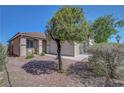 Well-maintained front yard with a mature tree, small seating area, and low-maintenance landscaping at 4020 Driscoll Mountain St, Las Vegas, NV 89129