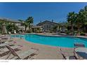 Community pool with lounge chairs and palm trees on a sunny day at 5710 E Tropicana Ave # 2178, Las Vegas, NV 89122