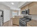 Modern kitchen with stainless steel appliances, light wood cabinets, and beautiful natural light through shuttered windows at 6480 Annie Oakley Dr # 112, Las Vegas, NV 89120