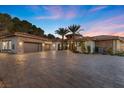 Spacious home with a circular entryway, 3-car garage, and a large brick driveway lined with mature palm trees at 1 Costa Del Sol Ct, Henderson, NV 89011
