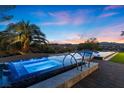 Beautiful backyard at twilight, featuring a modern pool and spa with city views and palm trees at 1 Costa Del Sol Ct, Henderson, NV 89011