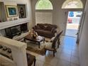 Cozy living room with tile floors, a decorative fireplace, and abundant natural light from front windows at 10968 Geyser Peak St, Henderson, NV 89052