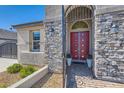 Close-up of the home's entry; features stone accents, and a decorative door; manicured shrubs at 130 W Fairway Rd, Henderson, NV 89015