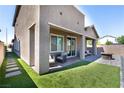 Backyard featuring a covered patio area, grass lawn, rock feature, and stylish outdoor furniture at 4376 Latitude Valley Ct, North Las Vegas, NV 89084