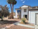 Two-story home with a front yard, featuring desert landscaping, palm trees, and an attached garage at 5243 Sunnywood Dr, Las Vegas, NV 89120