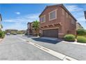 View of a row of townhomes with desert landscaping and attached garages at 715 Taliput Palm Pl, Henderson, NV 89011