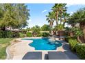 Beautiful pool and spa feature alongside lounge chairs and lush palm tree landscaping at 8121 Eagle Clan Ct, Las Vegas, NV 89131