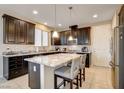 Kitchen features a large island with seating, granite counters, dark wood cabinets, and stainless appliances at 9846 Sunriver Meadows Ave, Las Vegas, NV 89148