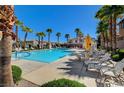 Community pool area featuring palm trees, ample seating, and sparkling blue water under a clear sky at 6255 W Arby Ave # 258, Las Vegas, NV 89118
