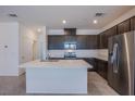 Modern kitchen features stainless steel appliances, a central island with quartz countertops, and dark wood cabinetry at 6288 Dolosonte St, Las Vegas, NV 89113