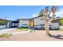 Charming single-story home featuring a vibrant yellow door, xeriscaped landscaping, and covered carport at 237 Cervantes St, Las Vegas, NV 89101