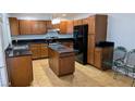 Spacious kitchen featuring brown cabinets, black countertops, and a functional center island at 3020 Wilmington Way, Las Vegas, NV 89102
