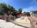 View of a fenced in front yard with desert landscaping, mature trees and a walkway at 5600 Grossmont Ave, Las Vegas, NV 89110