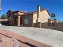 A two-story home featuring a red tile roof, desert landscaping, and a secure gated driveway at 7020 King Solomons Ct, Las Vegas, NV 89117