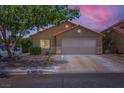 Charming single-story home featuring a two-car garage, desert landscaping, and a welcoming facade at dusk at 8934 Libertyvale Dr, Las Vegas, NV 89123