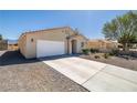 Single-story house featuring a two-car garage, desert landscaping, and wide driveway at 100 Eton St, Pahrump, NV 89048