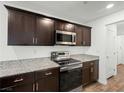 Modern kitchen with dark cabinets, granite countertops, and stainless steel appliances at 12112 Polar White Ct # 3, Las Vegas, NV 89183