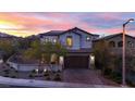 Charming two-story home featuring desert landscaping, a brick driveway, and a beautiful sunset sky at 11856 Barona Mesa Ave, Las Vegas, NV 89138