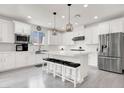 Modern kitchen featuring white cabinets, stainless steel appliances, an island with seating, and light wood flooring at 11856 Barona Mesa Ave, Las Vegas, NV 89138