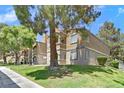Exterior view of condo buildings with well-maintained lawn and mature trees at 230 Mission Newport Ln # 104, Las Vegas, NV 89107