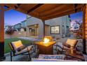 Relaxing backyard seating area with a fire pit, complemented by lush landscaping and a covered patio at 2367 Ridgeline Wash St, Las Vegas, NV 89138