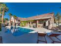 Gorgeous backyard with a swimming pool, lounge chairs, covered patio, and lush landscaping for relaxation and enjoyment at 3088 Paseo Mountain Ave, Henderson, NV 89052