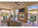 Covered outdoor living space featuring a fireplace, ceiling fan, television, and comfortable seating at 489 Open Hill Ave, Henderson, NV 89011