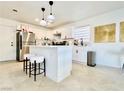 A well-lit kitchen with white cabinets, stainless steel appliances, island, and travertine floors at 5984 Emerald Canyon Dr, Las Vegas, NV 89142