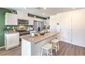 Modern kitchen featuring stainless steel appliances, white cabinets, granite countertop island, and luxury vinyl plank flooring at 7351 Kyle Cove Dr # Lot 208, North Las Vegas, NV 89084