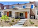 Inviting two-story townhome features an orange front door, low maintenance landscaping, and a concrete walkway at 10773 Bede Ct, Las Vegas, NV 89166