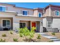 Inviting two-story townhome features an orange front door, low maintenance landscaping, and a concrete walkway at 10773 Bede Ct, Las Vegas, NV 89166