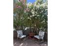 Landscaped patio featuring metal chairs and a small table, enclosed by mature foliage, and gray stone wall at 3464 Twilight Star Dr, Las Vegas, NV 89117