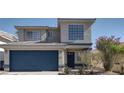 Charming two-story home with a blue garage door, well-manicured landscaping, and a large window at 5204 Padua Way, Las Vegas, NV 89107