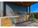 Modern outdoor kitchen featuring a built-in grill, stainless steel appliances, and a wooden cabinet at 6110 Pebble Glen Ct, Las Vegas, NV 89149
