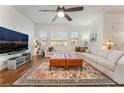 Comfortable living room with a plush white sectional, leather ottomans, ceiling fan, and a flat screen television at 715 Orange Plume Walk, Henderson, NV 89011