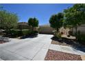 Inviting home exterior featuring a wide driveway, lush landscaping, and a two-car garage at 7727 Widewing Dr, North Las Vegas, NV 89084