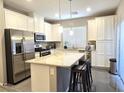 Bright kitchen features white cabinets, stainless steel appliances, granite countertops, and an island with bar stool seating at 8534 Insignia Ave # 101, Las Vegas, NV 89178