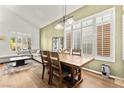 Dining area with hardwood floors, wooden table, shuttered windows and a view into the living room at 8612 Danza Del Sol Dr, Las Vegas, NV 89128