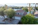 Exterior view of a two-story home on a lake with palm trees and mature trees at 8740 Captains Pl, Las Vegas, NV 89117