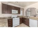 Well-lit kitchen featuring granite countertops, white appliances, and dark wood cabinets at 9305 Hollycrest Dr, Las Vegas, NV 89117