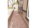 Narrow side yard with rock landscaping and the exterior of the property and windows at 167 Desert Pond Ave, Henderson, NV 89002