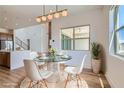 Elegant dining area with a round glass table, modern chandelier, and bright window at 182 Robledo St, Las Vegas, NV 89138